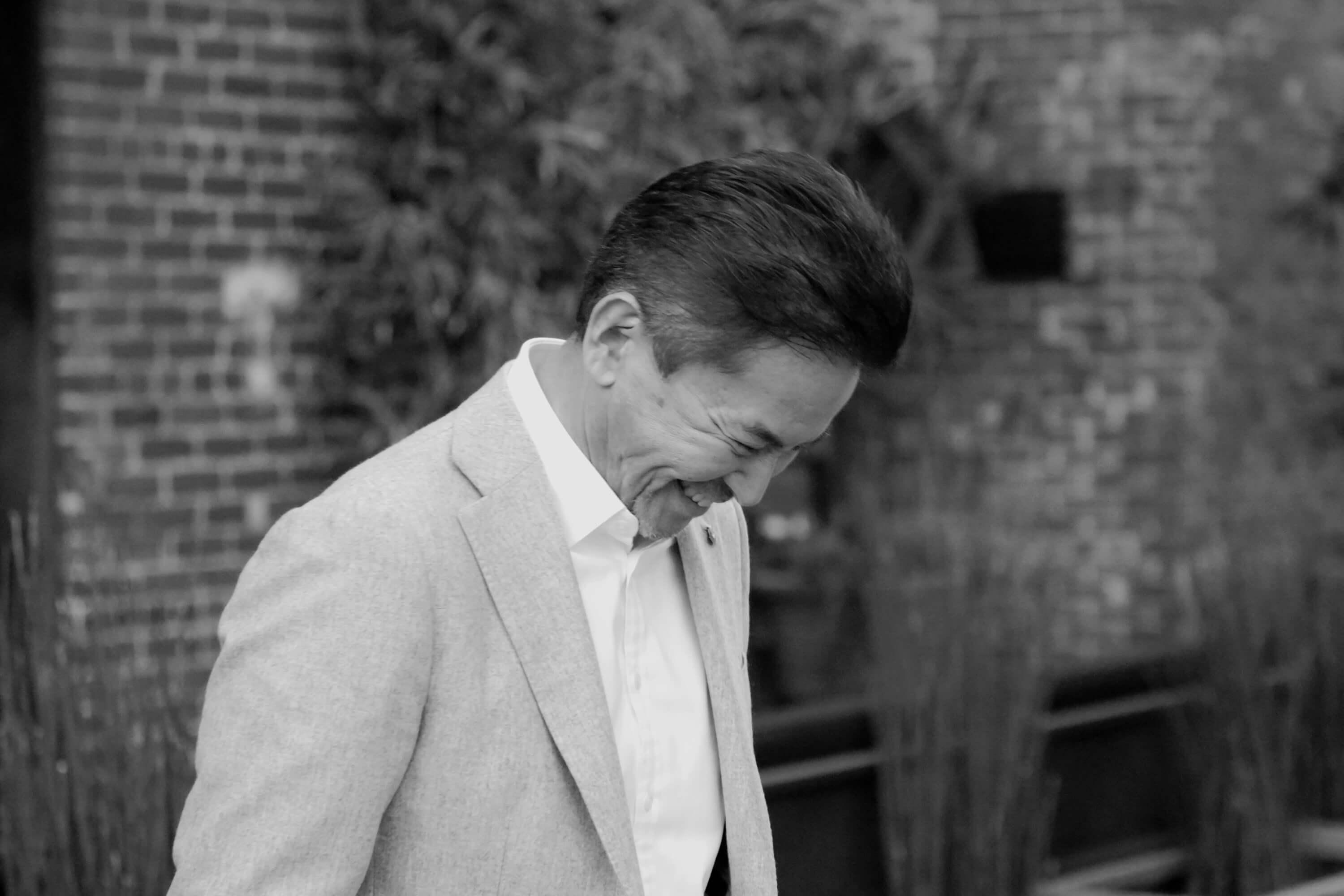 Black and white profile portrait of Rick. He wears a light-colored blazer and white shirt. He gazes downward with a kind smile.